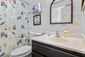 Bathroom featuring vanity, toilet, and curtained shower