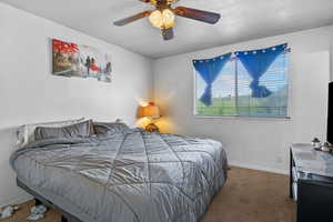 Carpeted bedroom featuring baseboards and a ceiling fan