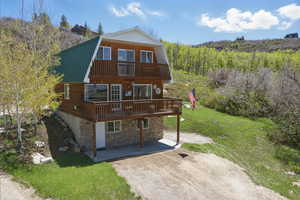 Back of property featuring a patio area, a gambrel roof, a yard, stone siding, and metal roof