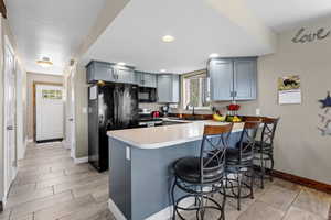 Kitchen with black appliances, a peninsula, baseboards, a sink, and a kitchen breakfast bar