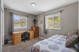 Carpeted bedroom featuring multiple windows, baseboards, and a desk