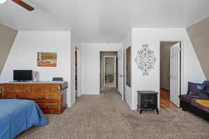 Bedroom with light colored carpet, baseboards, ceiling fan, and a wood stove