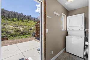 Laundry room featuring estacked washer and dryer and baseboards