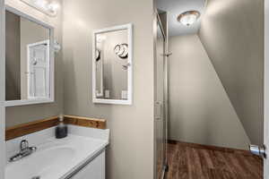 Bathroom featuring wood finished floors, vanity, and a shower with shower door