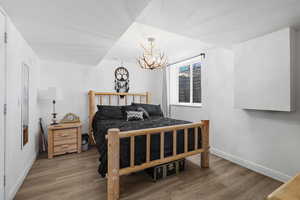 Bedroom featuring wood finished floors, a chandelier, and baseboards