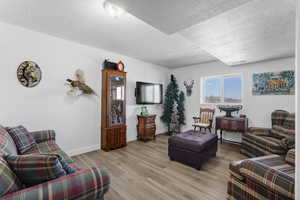 Living area featuring a textured ceiling, light wood-style floors, and baseboards