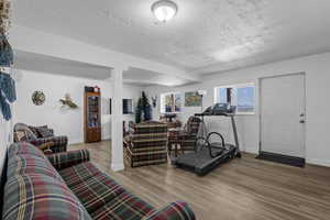 Living area featuring wood finished floors, a textured ceiling, and baseboards