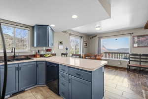 Kitchen with a peninsula, a sink, black dishwasher, blue cabinets, and recessed lighting