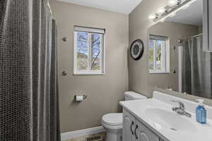 Full bath featuring toilet, vanity, baseboards, a shower with shower curtain, and tile patterned floors