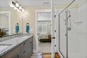 Full bath with connected bathroom, a shower stall, double vanity, a textured ceiling, and wood finished floors