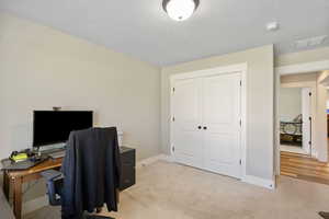 Office space with baseboards, light carpet, and a textured ceiling