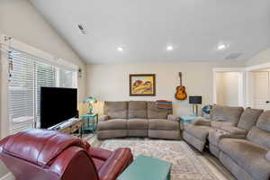 Living room with wood finished floors, recessed lighting, lofted ceiling, and a textured ceiling