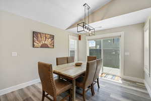 Dining area featuring lofted ceiling, wood finished floors, baseboards, and a textured ceiling