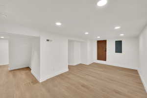 Empty room with electric panel, recessed lighting, light wood-style floors, and baseboards