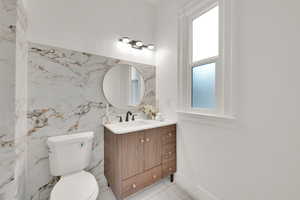 Half bathroom with plenty of natural light, vanity, and toilet