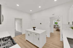 Kitchen featuring light wood-style floors, white cabinetry, recessed lighting, stovetop, and light stone counters