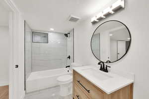 Bathroom featuring vanity, toilet, bathtub / shower combination, a textured ceiling, and recessed lighting