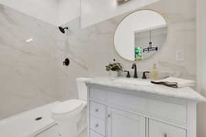 Bathroom with vanity, a marble finish shower, tile walls, toilet, and a chandelier