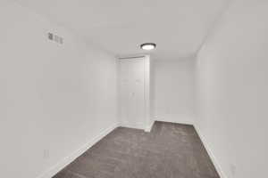 Empty room with dark carpet and baseboards