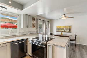 Kitchen with appliances with stainless steel finishes, a peninsula, wood finished floors, and a ceiling fan