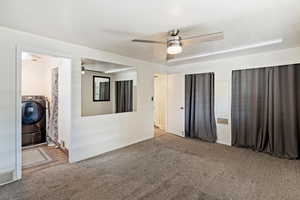 Spare room featuring washer / dryer, ceiling fan, and carpet flooring