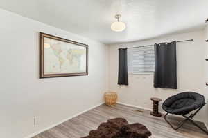 Living area with wood finished floors, baseboards, and a textured ceiling