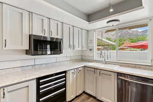 Kitchen with stainless steel appliances, a sink, wine cooler, dark wood-type flooring, and white cabinets