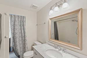Full bathroom with vanity, toilet, and curtained shower