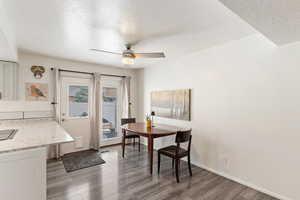Dining room featuring a textured ceiling, wood finished floors, a ceiling fan, and baseboards