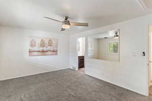 Carpeted spare room with ceiling fan, baseboards, and a textured ceiling