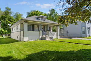 Bungalow featuring a front lawn, brick siding, and covered porch