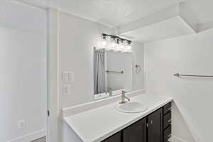 Bathroom featuring a textured ceiling, vanity, and baseboards