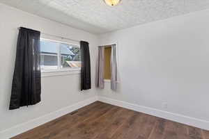 Empty room featuring dark wood finished floors and baseboards