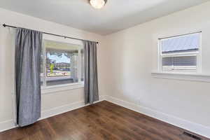 Empty room featuring baseboards and dark wood finished floors