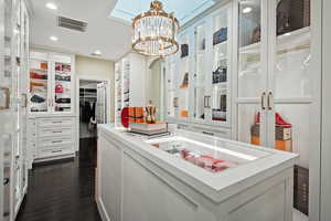 Spacious closet with dark wood finished floors and a chandelier