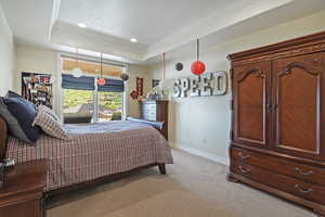 Bedroom with light carpet, a raised ceiling, baseboards, crown molding, and recessed lighting