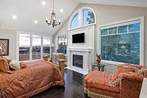 Bedroom featuring dark wood finished floors, a chandelier, access to exterior, recessed lighting, and a fireplace
