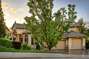 French country home with stone siding, roof with shingles, driveway, and stucco siding
