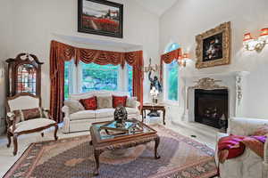 Living room featuring high vaulted ceiling, a fireplace, and baseboards