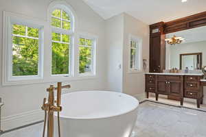 Bathroom featuring marble tiled flooring, vanity, baseboards, a freestanding bath, and recessed lighting