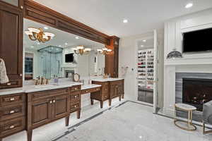 Bathroom featuring a glass covered fireplace, a chandelier, a stall shower, vanity, and baseboards