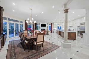 Dining area featuring a chandelier, recessed lighting, french doors, decorative columns, and light tile patterned floors