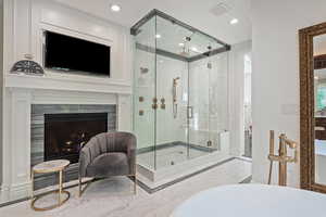 Bathroom featuring a freestanding tub, a stall shower, marble tiled floors, a fireplace, and recessed lighting
