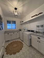 Laundry area with washer and dryer, cabinet space, a textured ceiling, a chandelier, and light tile patterned floors
