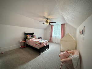 Bedroom with a textured ceiling, vaulted ceiling, carpet, ceiling fan, and baseboards