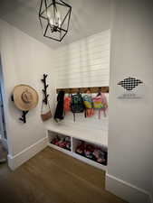 Mudroom featuring wood finished floors, a chandelier, and baseboards