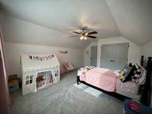 Bedroom with vaulted ceiling, carpet, a textured ceiling, and ceiling fan