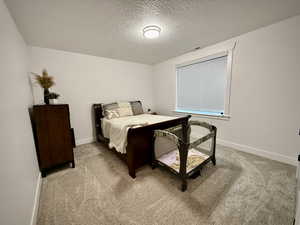 Bedroom featuring a textured ceiling, light carpet, and baseboards