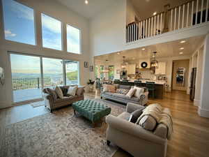 Living area featuring a high ceiling, light wood-type flooring, recessed lighting, and a chandelier