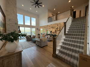 Living room featuring a high ceiling, hardwood / wood-style flooring, stairs, a ceiling fan, and recessed lighting